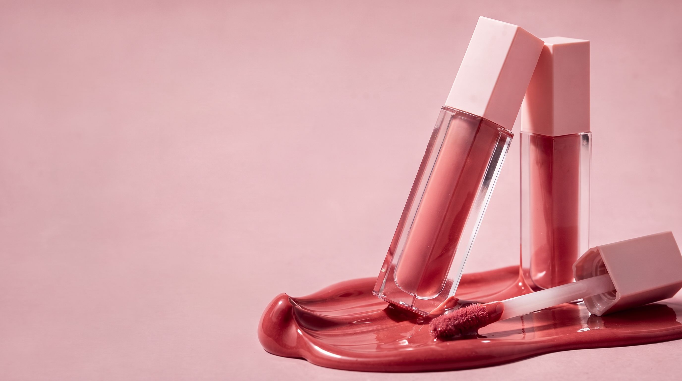 Rosy lip oils and a glossy pink color swatch, photographed with clean unprinted packaging